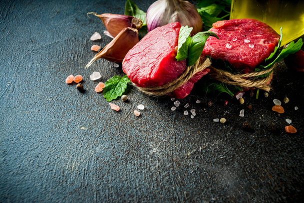 Ωμό βοδινό φιλέτο μινιόν μπριζόλες με μπαχαρικά και βότανα σε φόντο σκούρο συγκεκριμένο πίνακα - Φωτογραφία, εικόνα