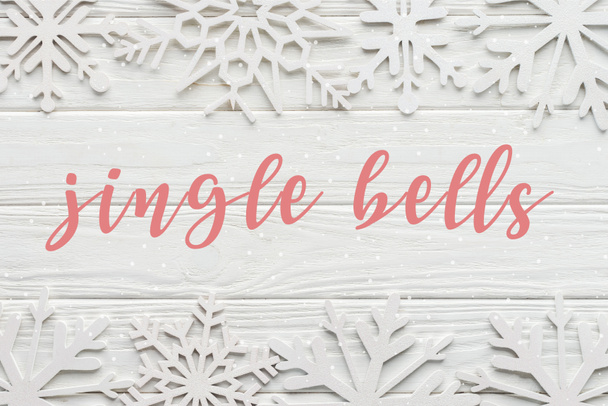 düz lay "yazı jingle bells" Beyaz ahşap zemin üzerine dekoratif kar taneleri ile  - Fotoğraf, Görsel