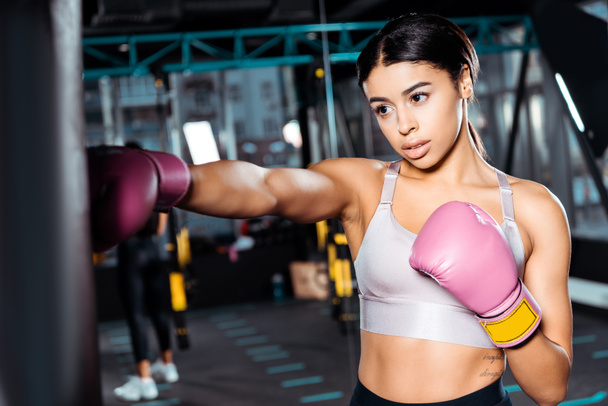 Menina boxeador atraente em luvas de boxe dando socos no ginásio
  - Foto, Imagem