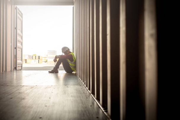 Gestresste verzweifelte Mitarbeiter in Logistikunternehmen sitzen in Containerkiste auf Werft - Foto, Bild