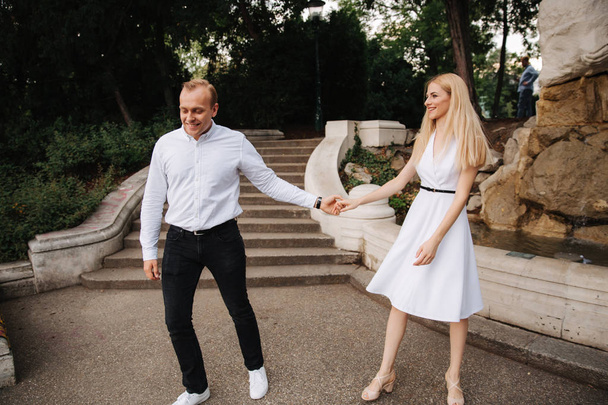 Nuori pariskunta kävelee puistossa. Pidä hauskaa ja iloitse. Mustavalkoiset vaatteet
 - Valokuva, kuva