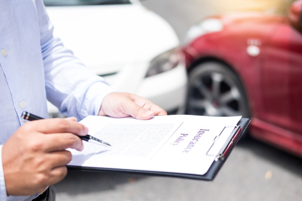 Agente assicurativo che scrive negli appunti durante l'esame dell'auto dopo la valutazione e l'elaborazione della domanda di infortunio
 - Foto, immagini