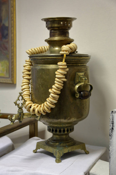 Устройство для кипячения воды и приготовления чая. Традиционный российский самовар с сушеными кольцеобразными рулонами
 - Фото, изображение