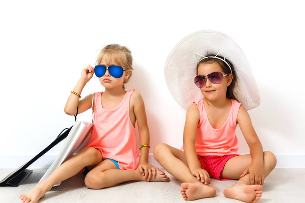 two little girls posing together in sunglasses on white background - Valokuva, kuva