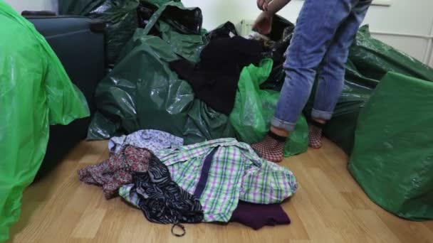 Kobieta z second hand, odzież w pobliżu torby plastikowe - Materiał filmowy, wideo