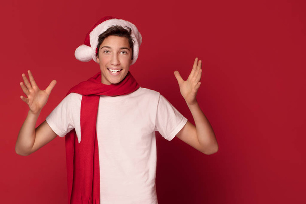 Щасливі підліток хлопчик постановки в Санта-Клауса капелюх, посміхаючись, фон червоний студії. - Фото, зображення