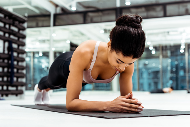Beautiful sportive girl doing plank on mat  in fitness gym - Photo, Image