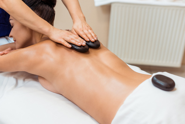 attractive young woman having hot stone massage in spa salon - Foto, Imagem