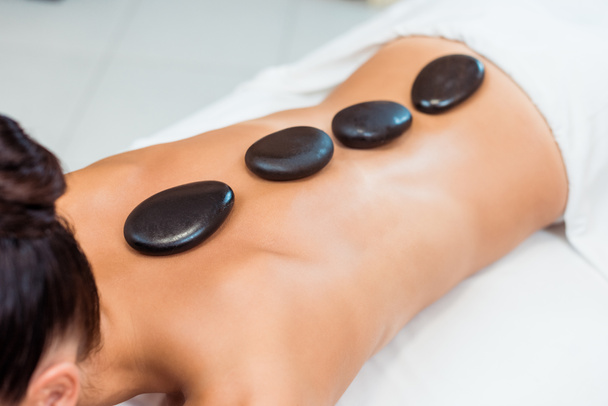 cropped shot of young woman having hot stone massage  - 写真・画像