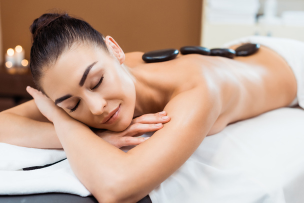 beautiful smiling girl enjoying hot stone massage in spa salon - Photo, Image