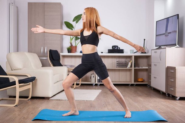 Mooie jonge vrouw verblijft in Warrior Ii yoga pose - Foto, afbeelding