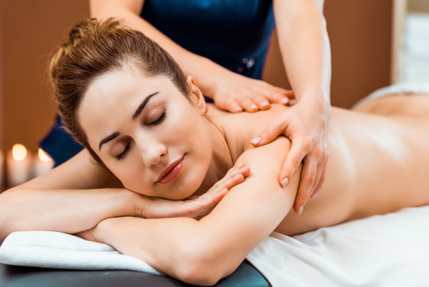 beautiful young woman with closed eyes enjoying massage in spa salon - Fotografie, Obrázek