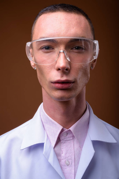 Young handsome androgynous man doctor wearing protective glasses - Φωτογραφία, εικόνα