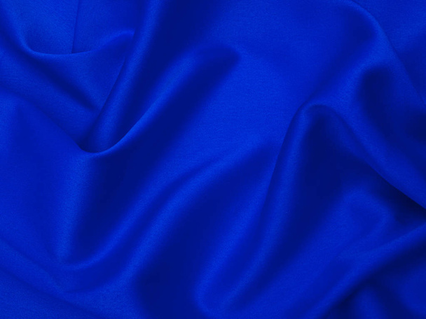 Blue fabric is laid out waves. Blue silk fabric for background or texture. - Fotoğraf, Görsel
