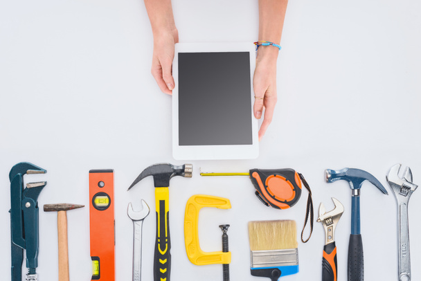 cropped shot of woman using tablet with various tools lying on white - Photo, Image