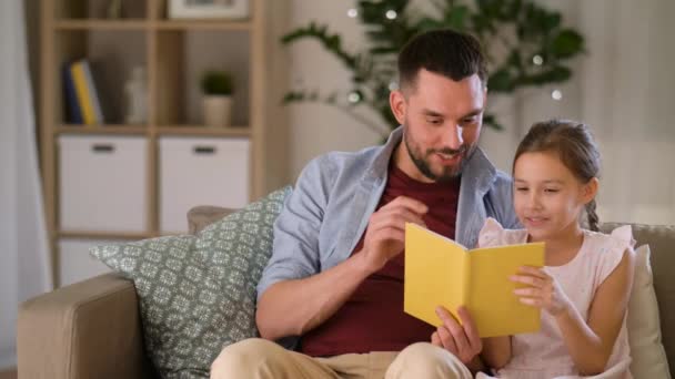 happy father and daughter reading book at home - Кадры, видео