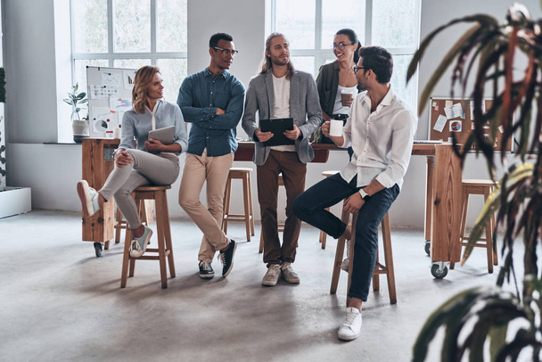 Corporate team aan houten tafel in creatieve moderne kantoor studio poseren en camera te kijken - Foto, afbeelding