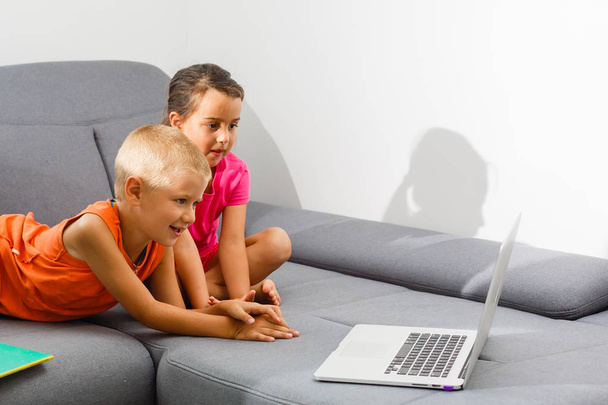 дві дитини використовують ноутбук вдома
 - Фото, зображення