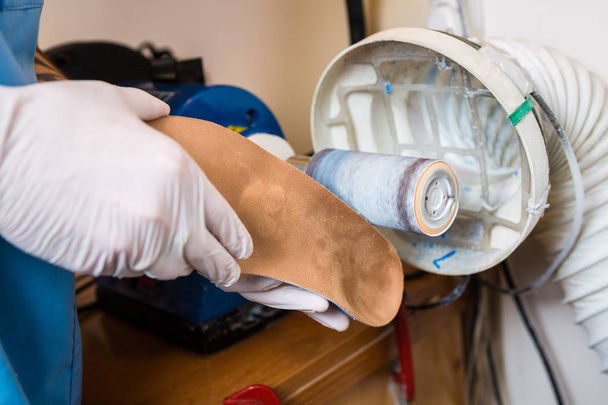 O processo de fabricação de palmilhas individuais ortopédicas para pessoas com doenças nas pernas, pés chatos. Close-up da mão de um homem de um empregado insta uma palmilha ortopédica em uma máquina-ferramenta em uma oficina
. - Foto, Imagem