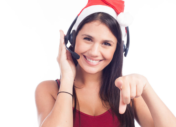 Christmas headset woman from telemarketing call center wearing red santa hat talking smiling isolated on white background. Woman pointing with finger - Foto, Imagem
