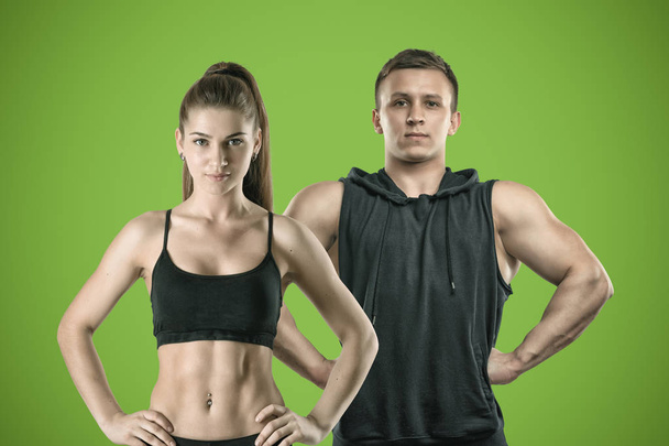 A young muscular woman and a fit man stand on a green background. - Fotó, kép