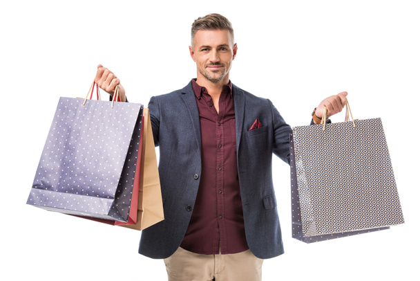 man in jacket showing colorful paper bags isolated on white - Foto, Imagen