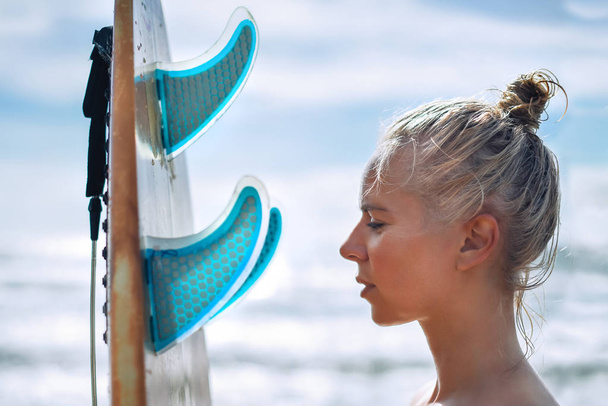 Beautiful girl surfer with a board at sunrise. Summer vacation at sea, healthy lifestyle. - Fotoğraf, Görsel