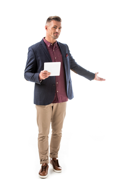 handsome stylish man in jacket holding digital tablet and doing invite gesture isolated on white - Valokuva, kuva