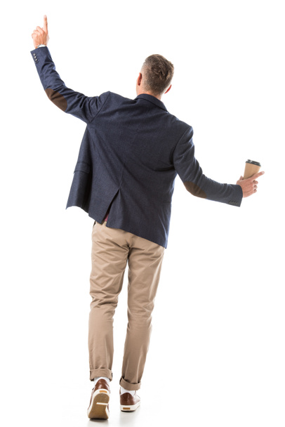 vista trasera del hombre con estilo en chaqueta gesto por las manos y sosteniendo taza de café de papel aislado en blanco
 - Foto, Imagen