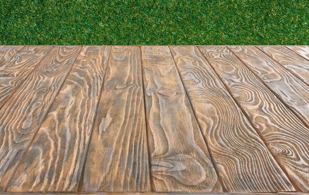  surface of brown wooden planks on green grass background - Fotografie, Obrázek