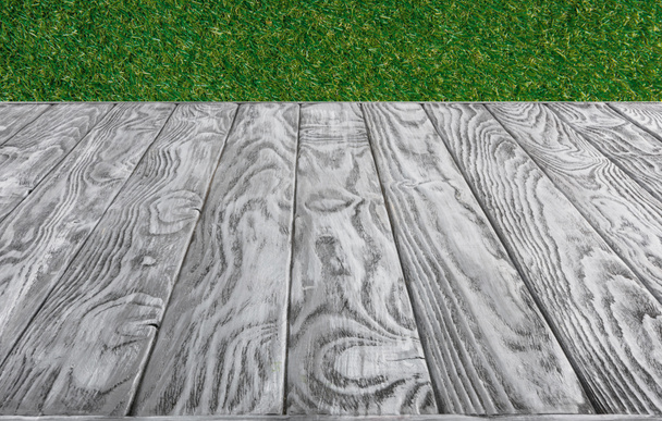  surface of grey wooden planks on green grass background - Foto, Imagem