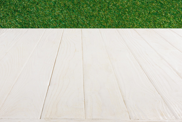  surface of white wooden planks on green grass background - Foto, Bild