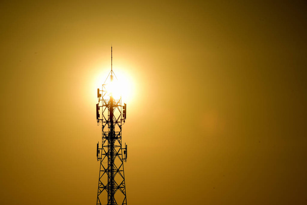 Antenne de communication sans fil avec ciel brillant.Tour de télécommunication avec antennes avec ciel bleu et doré
. - Photo, image