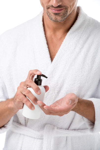 partial view of man in bathrobe using body lotion isolated on white - Foto, afbeelding