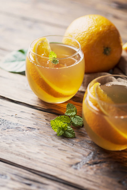 Cold tea with orange and mint on the wooden table, selective focus - Foto, Bild