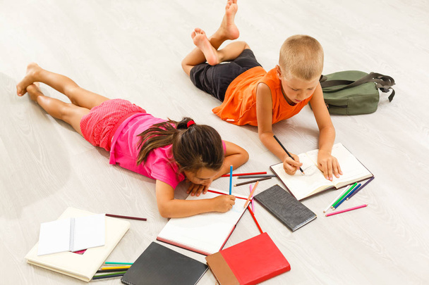 маленька дівчинка з хлопчиком дошкільного віку вивчає вдома на підлозі
  - Фото, зображення