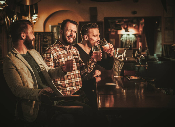 Velhos amigos se divertindo e bebendo cerveja rascunho no balcão de bar no pub
. - Foto, Imagem