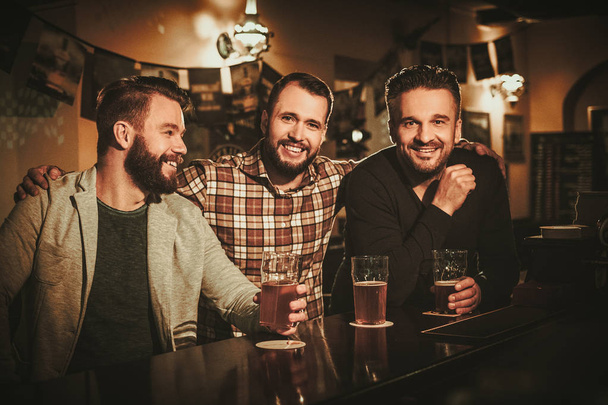 Velhos amigos se divertindo e bebendo cerveja rascunho no balcão de bar no pub
. - Foto, Imagem