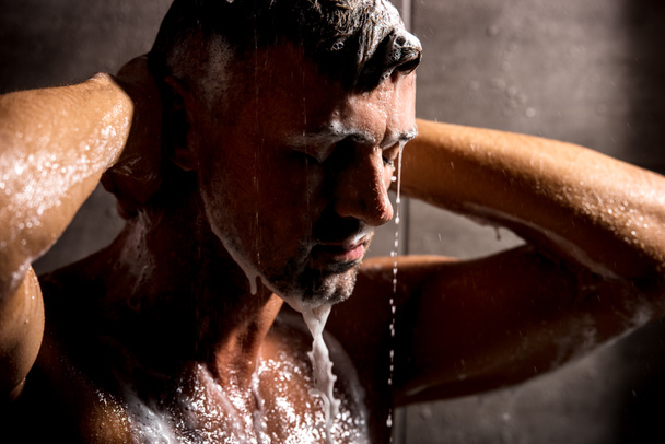 zár-megjelöl kilátás-felnőtt ember csukott szemmel hab mosás a zuhany alatt  - Fotó, kép