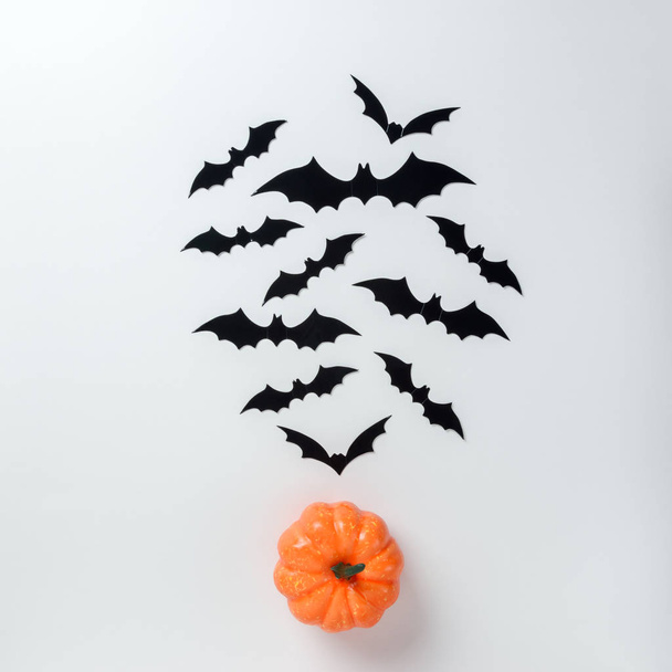 Halloween holiday minimal top view of bats and pumpkin on white background. Halloween minimal concept. - Fotó, kép