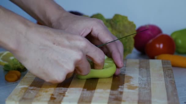 Az ember a vágás zöldség a konyhában, szeletelés zöld színű paprika - Felvétel, videó