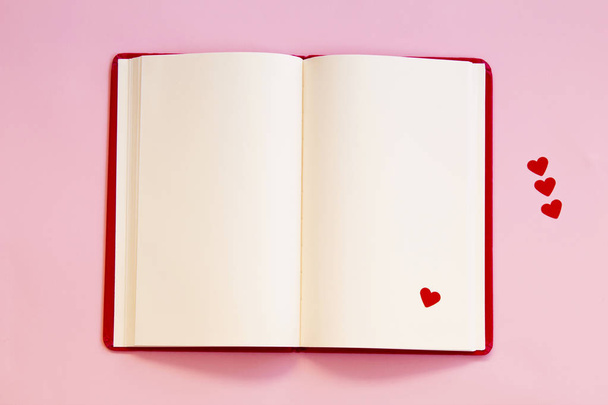 notitieblok openen met rood hart op roze achtergrond - Foto, afbeelding