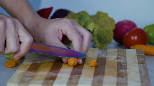 Homem está cortando legumes na cozinha, cortando cenoura
 - Filmagem, Vídeo