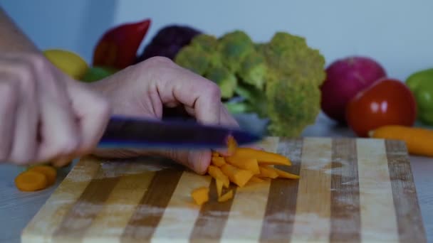 Mann schneidet Gemüse in der Küche, schneidet Möhren in Scheiben - Filmmaterial, Video