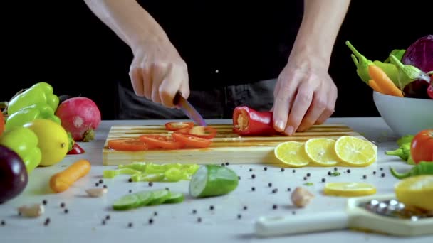 Ο άνθρωπος είναι κοπής λαχανικών στην κουζίνα, σε φέτες κόκκινο πιπέρι κουδουνιών - Πλάνα, βίντεο