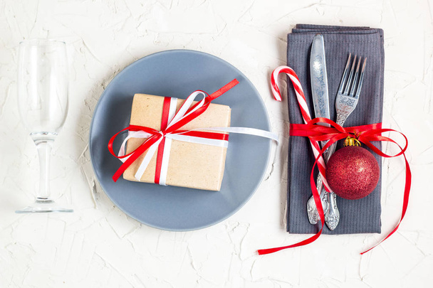 Kerst tabel couvert met servet, vork, mes, bal, plaat, snoep stokken, bril en cadeau. Kerst vakantie achtergrond. Plat leggen, Top uitzicht, kopie ruimte - Foto, afbeelding