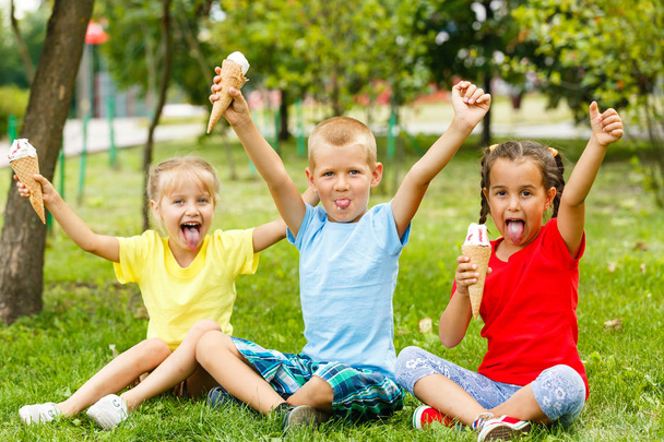 Μικρά παιδιά συνεδρίαση για την πράσινη χλόη και τρώνε παγωτό  - Φωτογραφία, εικόνα
