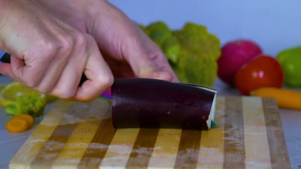 Mann schneidet Gemüse in der Küche, schneidet Auberginen - Filmmaterial, Video