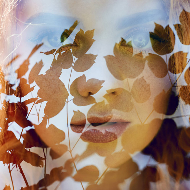 Fabulous portrait of a red-haired girl in nature with double exposure and glare. Beautiful redhead girl with long hair in the forest, mysterious look and big eyes, leaves and grass on her face - Φωτογραφία, εικόνα