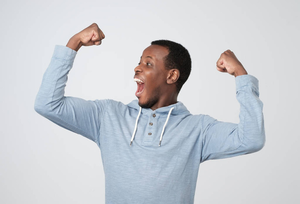 Happy successful african man winning, fists pumped celebrating success isolated grey wall background. Life perception, achievement - Фото, изображение